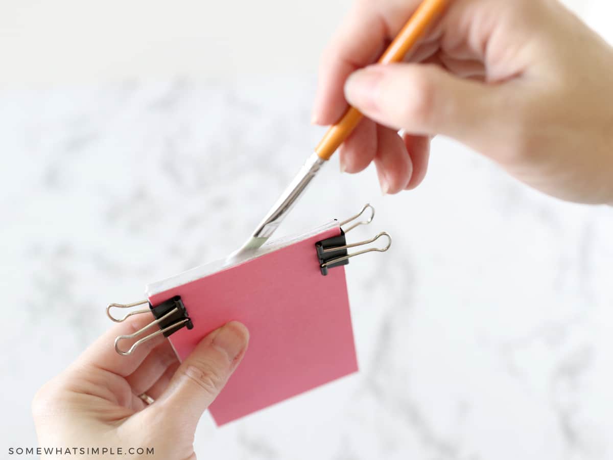 adding glue to a stack of paper