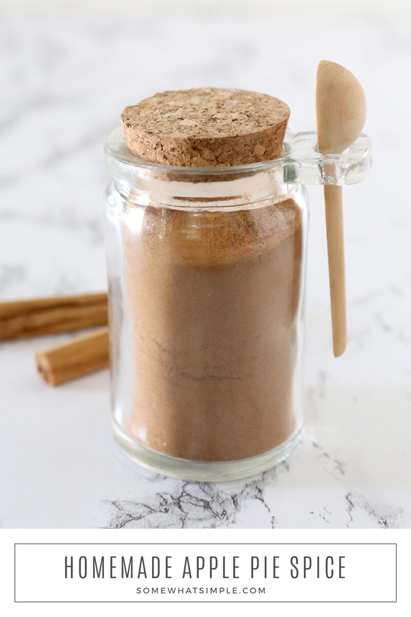 long image of homemade apple pie spice in a glass jar with small wooden spoon
