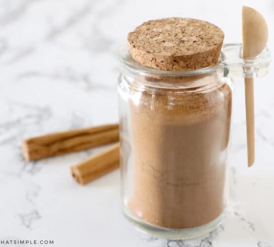 apple pie spice in a jar with cinnamon sticks behind it