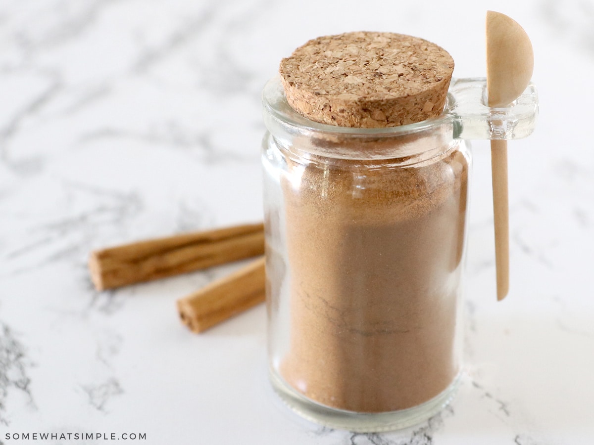 apple pie spice in a jar with cinnamon sticks behind it