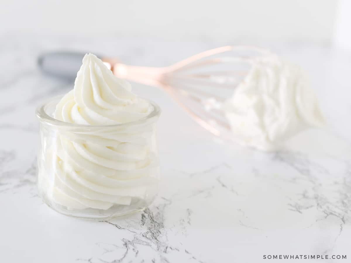 frosting in a small glass jar with a whisk in the background