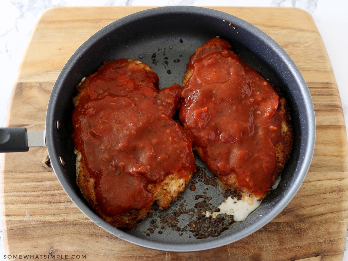 pouring sauce on top of chicken breasts