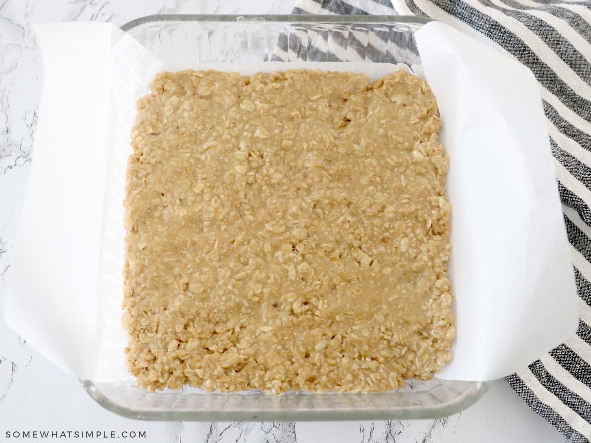 pressing granola mixture into a baking dish lined with parchment paper