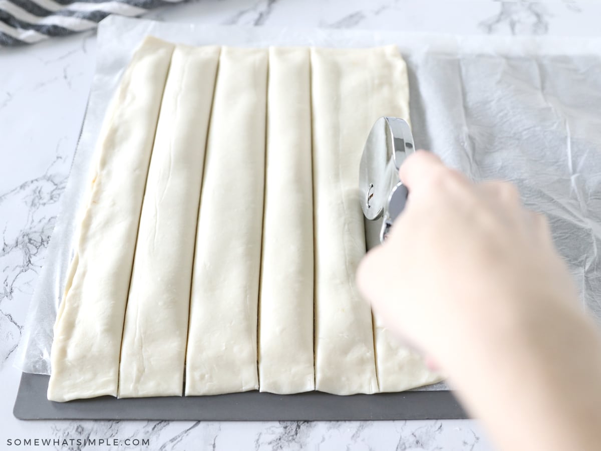placing puff pastry on top of pumpkin mixture and cutting the pastry into strips