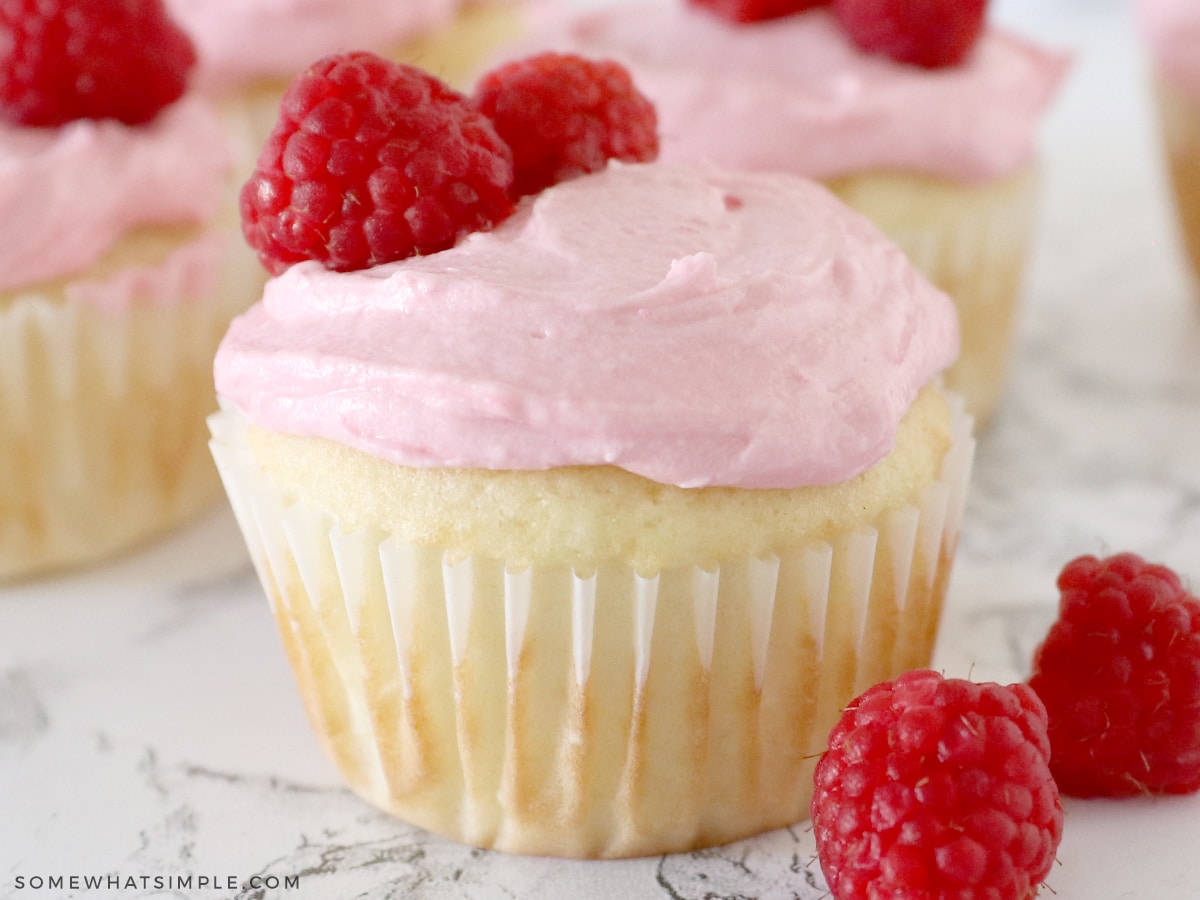 close up of a vanilla cupcake topped with raspberry buttercream frosting