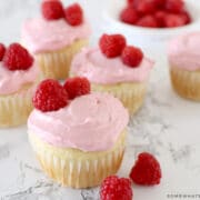 vanilla cupcakes with raspberry buttercream frosting garnished with fresh raspberries