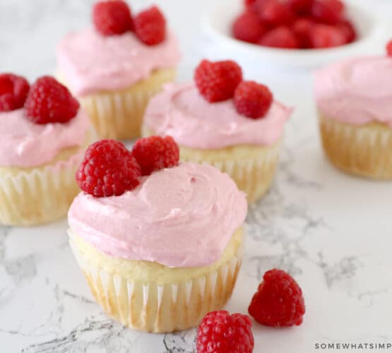 vanilla cupcakes with raspberry buttercream frosting garnished with fresh raspberries