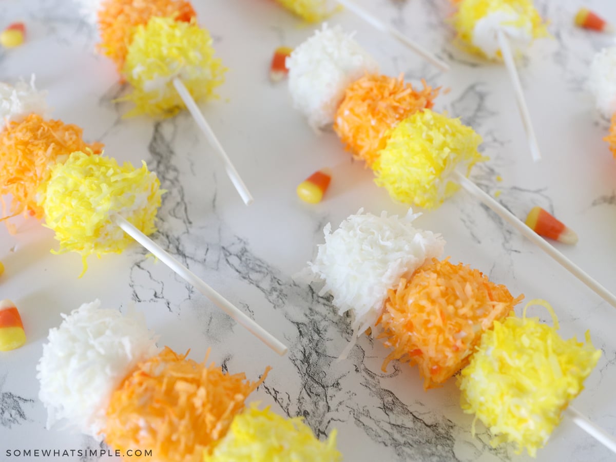 chocolate and coconut covered marshmallows in candy corn colors on a stick