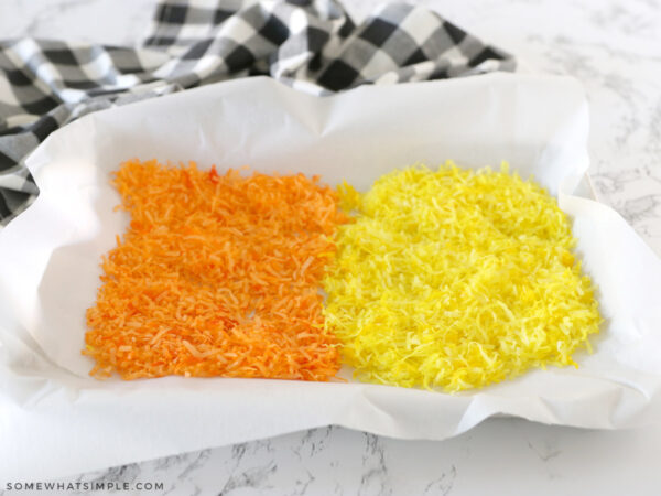 orange and yellow dyed coconut flakes on parchment paper