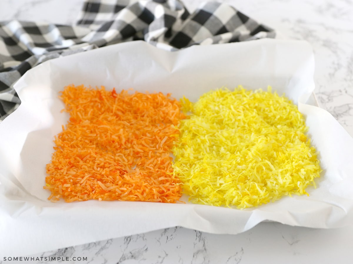orange and yellow dyed coconut flakes on parchment paper