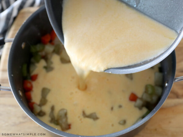 adding cheese and milk to a pot of soup