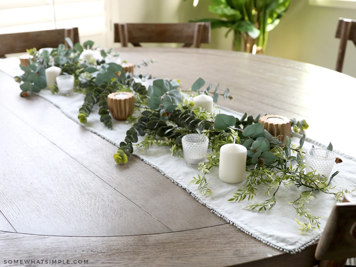 adding candles to the greenery of a fall centerpiece