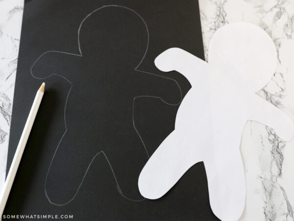 tracing a mummy outline onto a black piece of paper