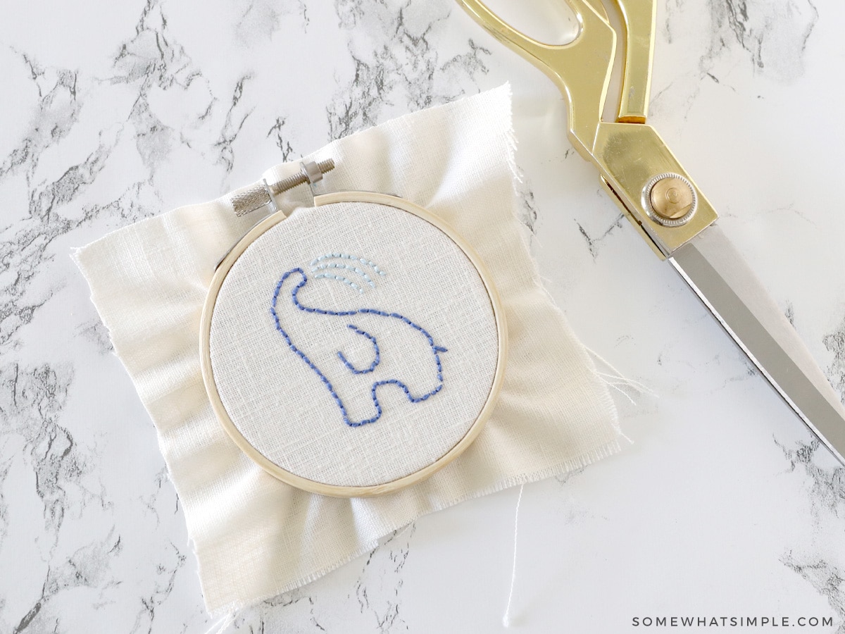 trimming the excess fabric around an embroidery hoop