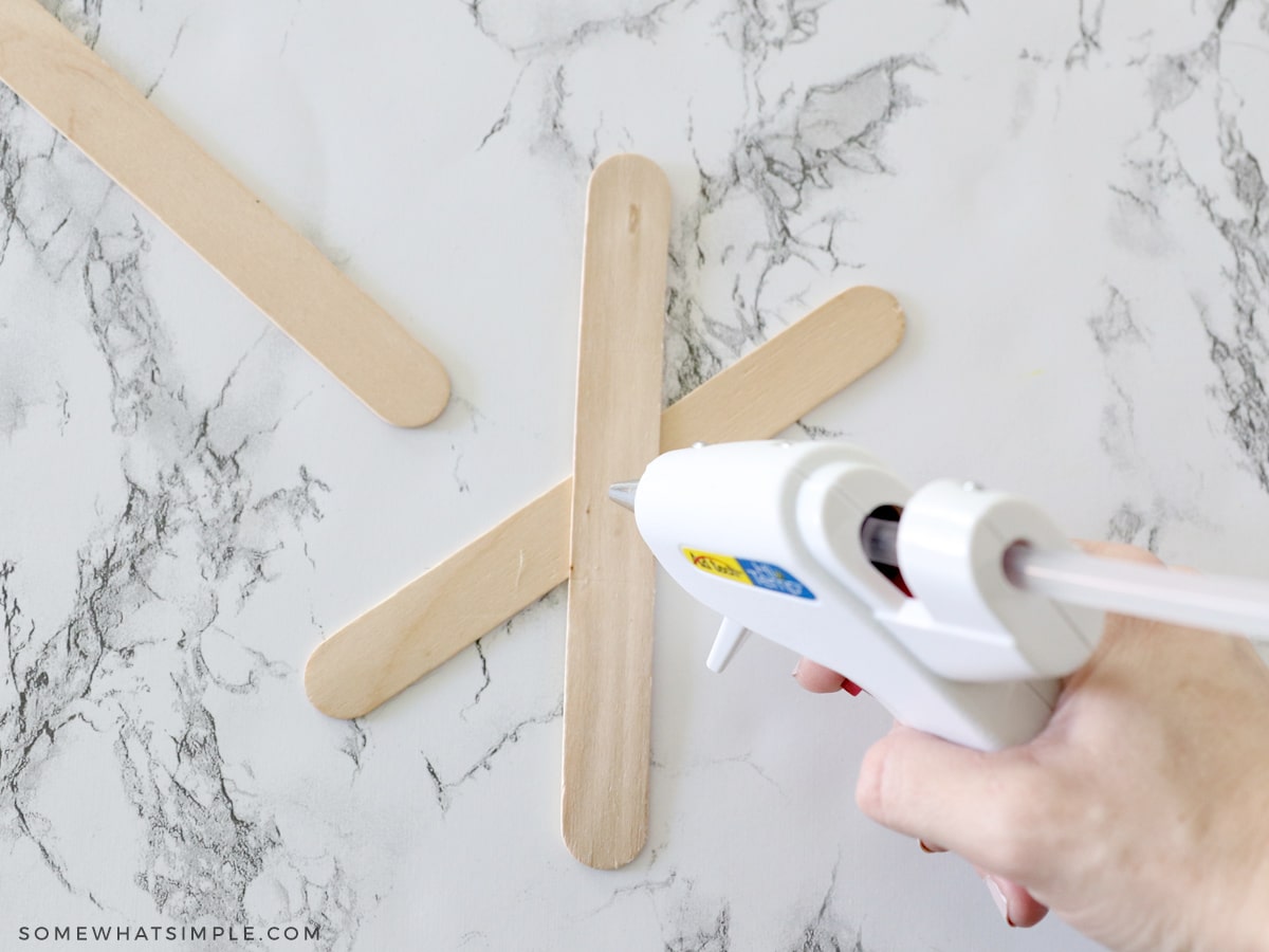 glueing popsicle sticks on top of each other to make a spider web