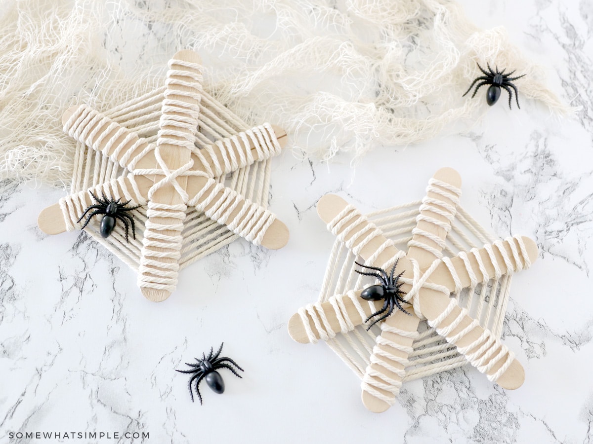 adding plastic spiders to a popsicle stick web