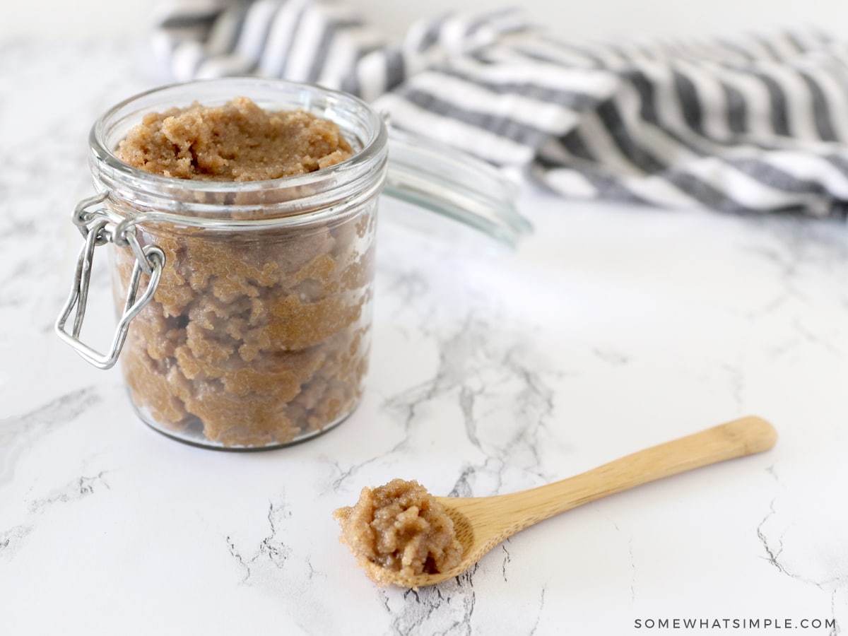 brown sugar scrub in a glass jar with a wooden spoon