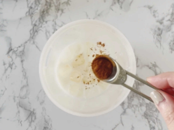 adding cinnamon to a glass of milk