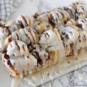 apple cinnamon bread on a white cutting board drizzled with frosting