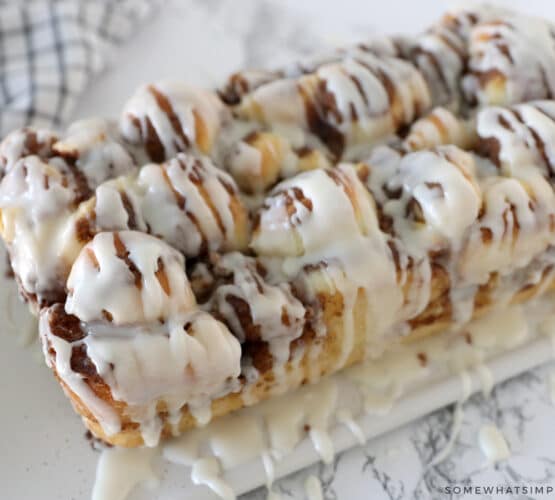 apple cinnamon bread on a white cutting board drizzled with frosting