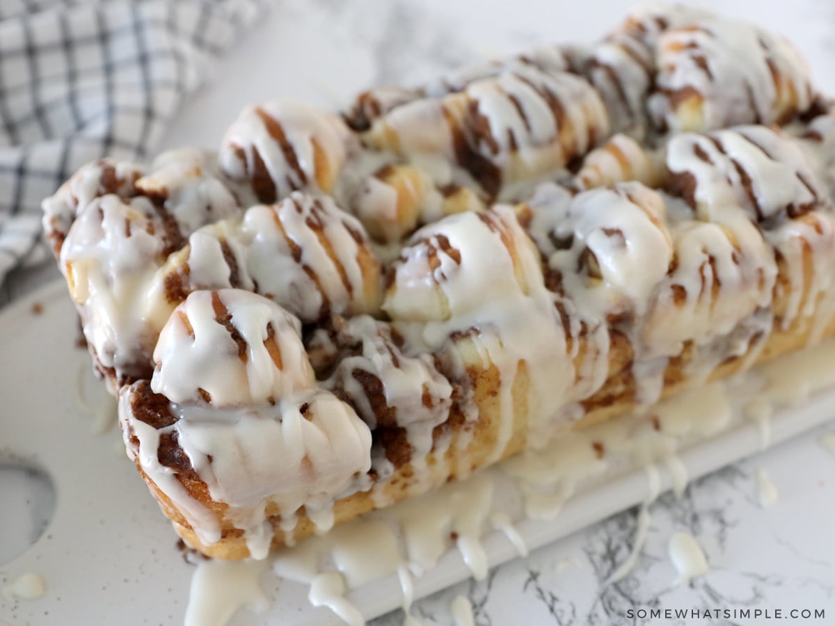 apple cinnamon bread on a white cutting board drizzled with frosting