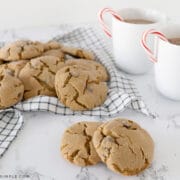 a plate of soft gingerbread cookies next to hot cocoa