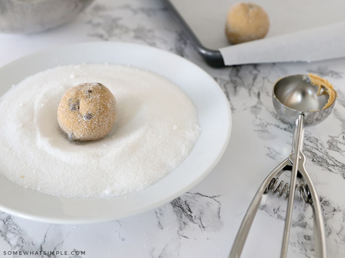 rolling cookie dough balls in white sugar