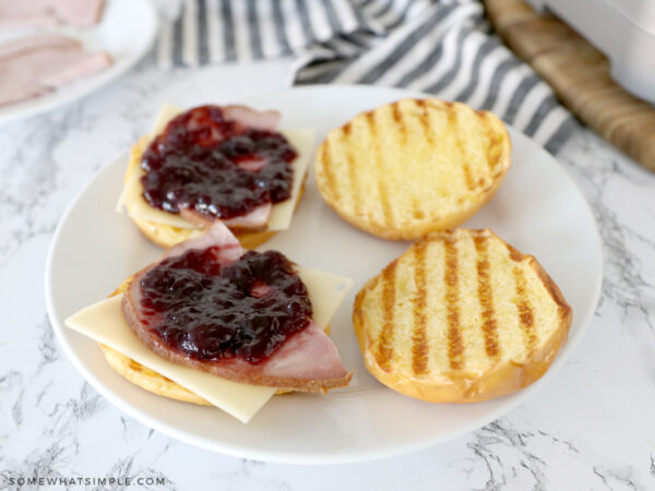 building a ham sandwich on a white plate