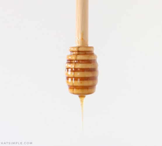 hot honey dripping off a wooden honey spoon