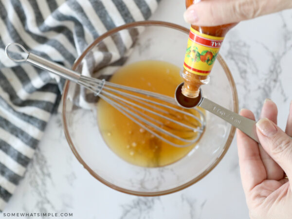adding hot sauce to a bowl of honey