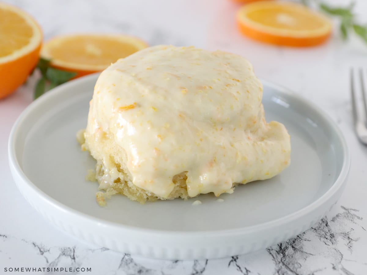 1 orange roll on a plate with slices of oranges in the background