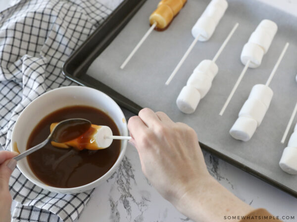 dipping marshmallows into caramel