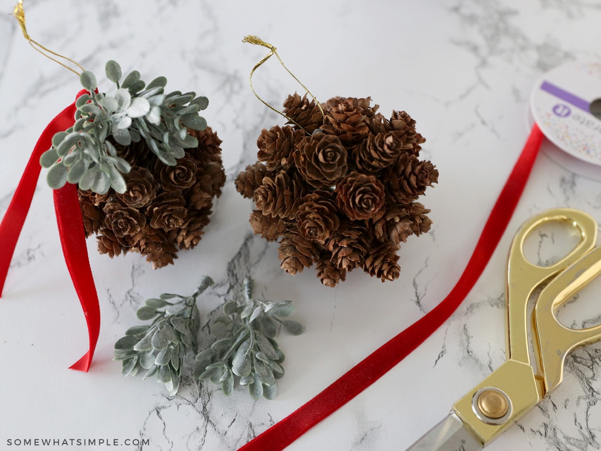 adding greenery and ribbon to a pinecone topiary