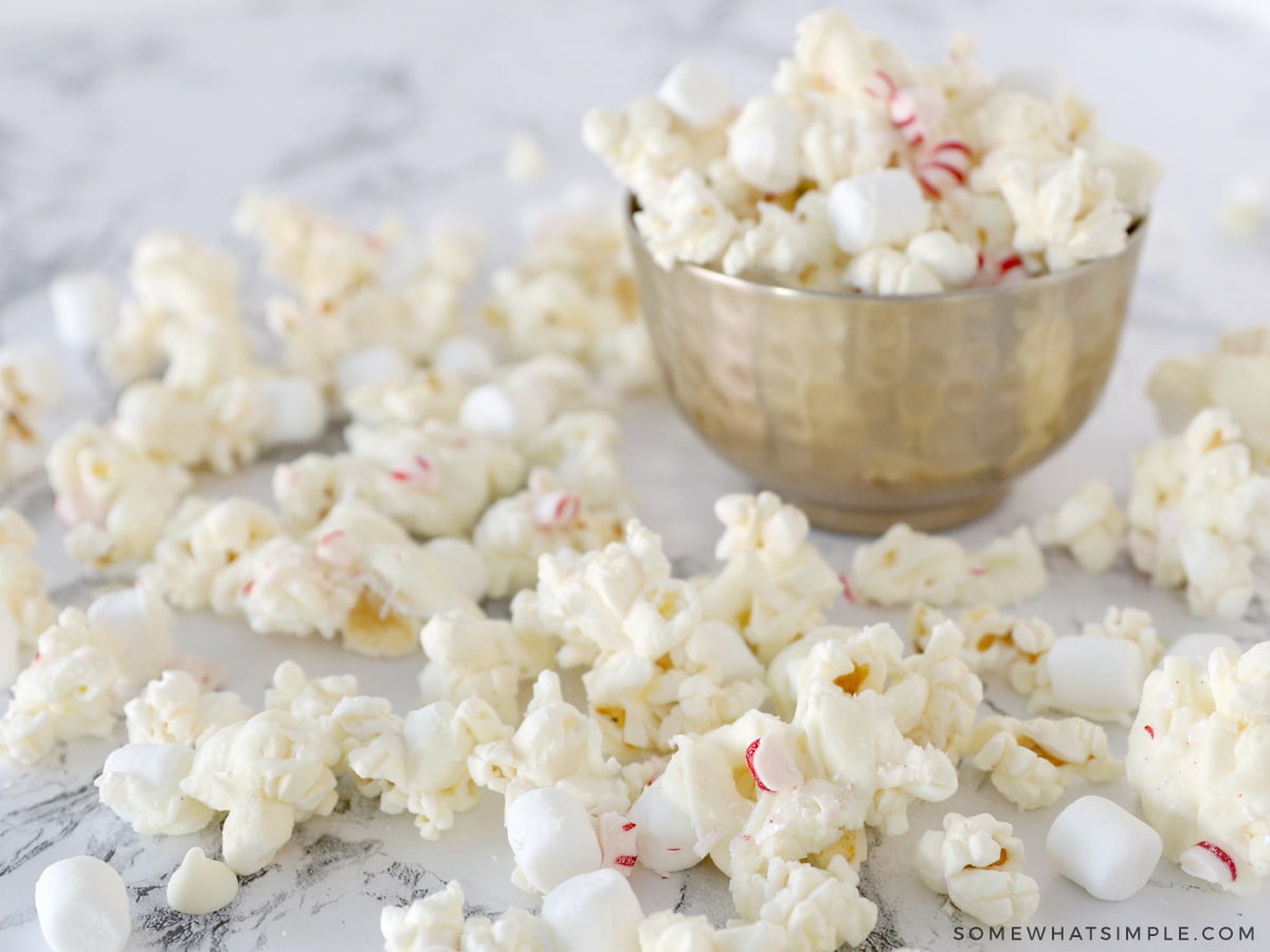 small bowl with white chocolate popcorn in and around it 