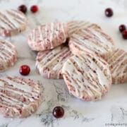 cranberry orange shortbread cookies on a white counter with fresh cranberries around them