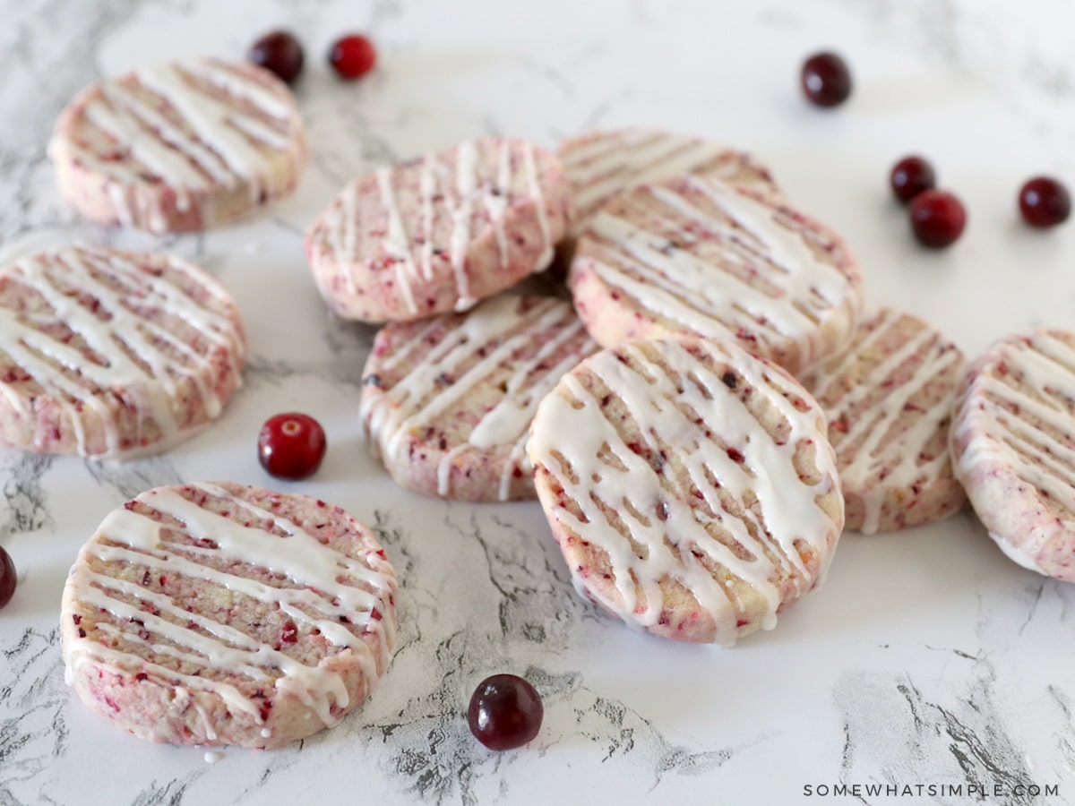 cranberry orange shortbread cookies on a white counter with fresh cranberries around them