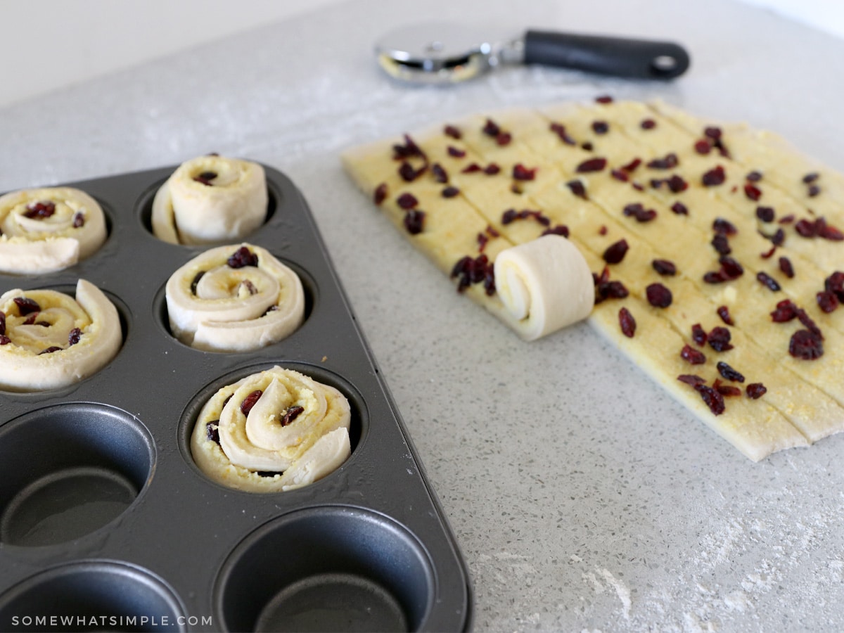 adding rolled dough to a muffin tin