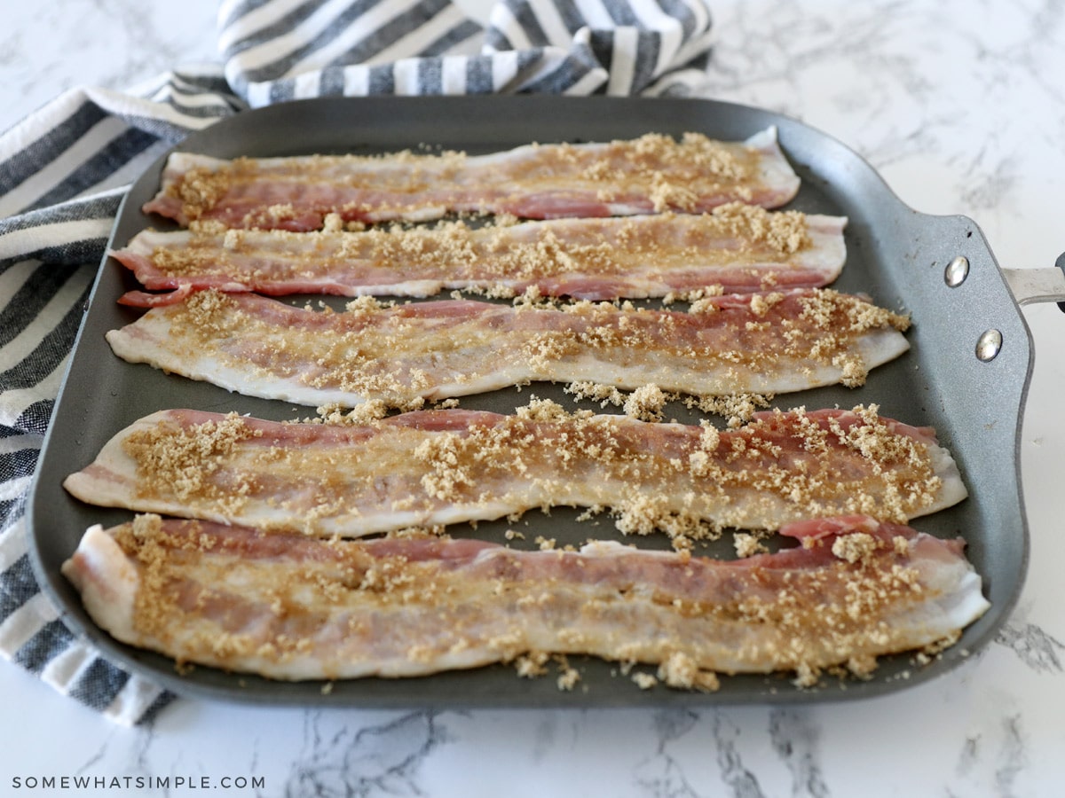 adding brown sugar to strips of raw bacon on a griddle