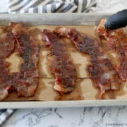 adding candied bacon to a baking sheet to cool