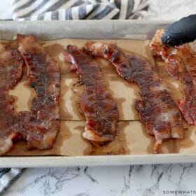 adding candied bacon to a baking sheet to cool
