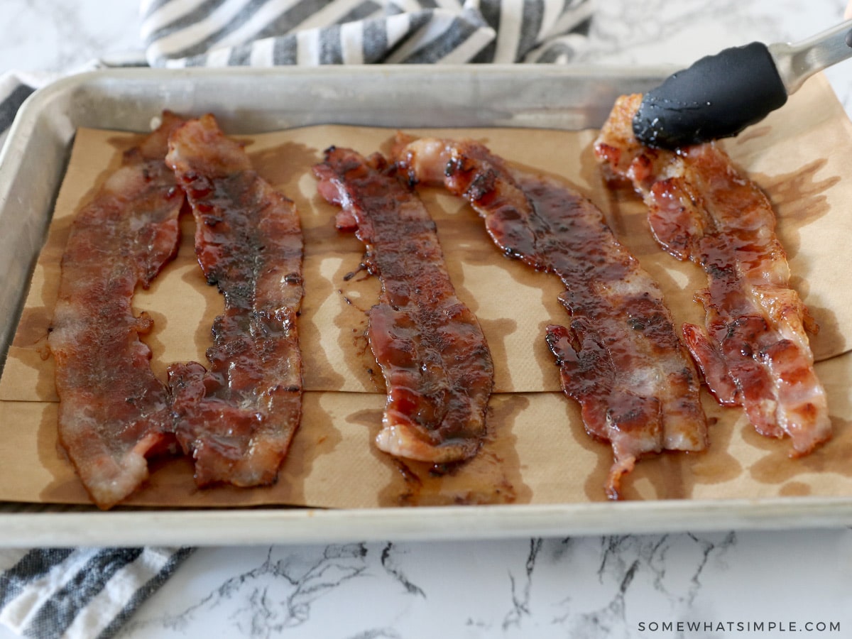 adding candied bacon to a baking sheet to cool