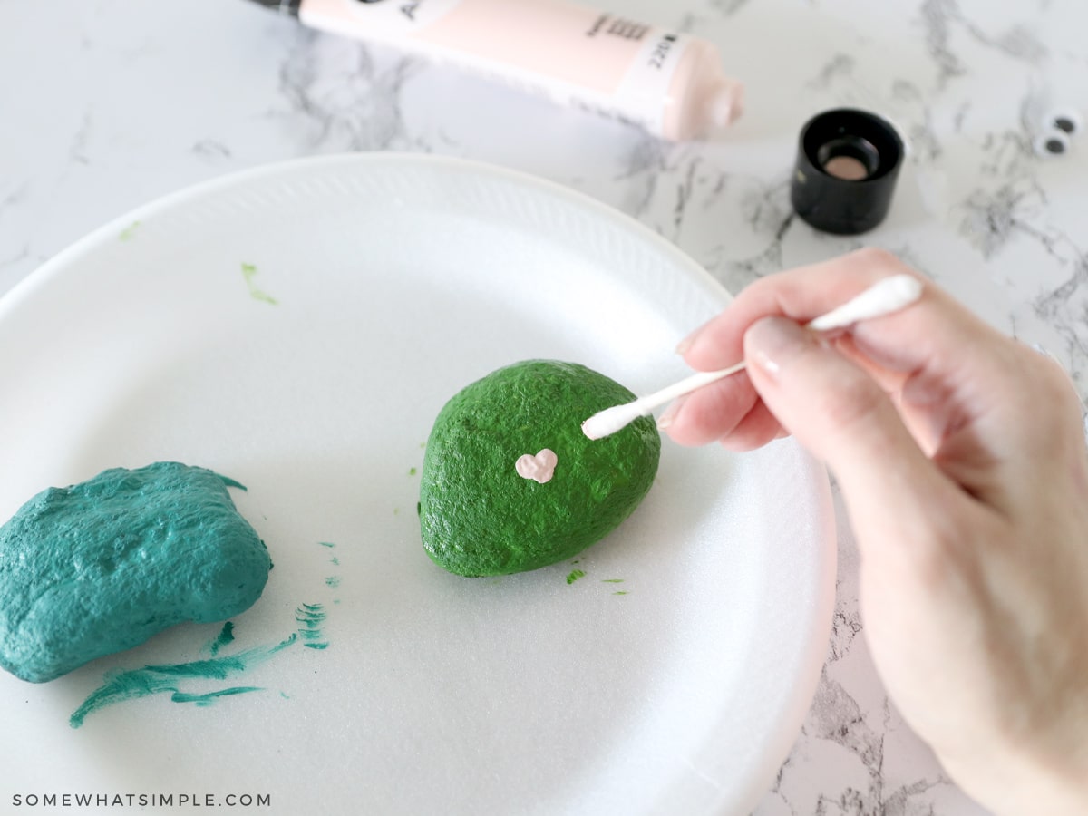 painting a heart-shaped mouth on a green river rock