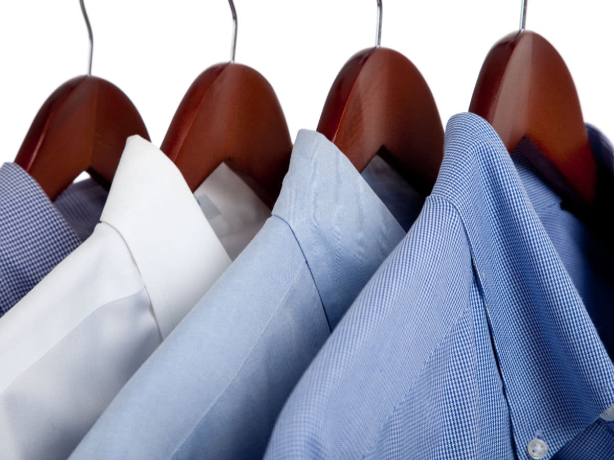 4 mens dress shirts hanging on wood hangers