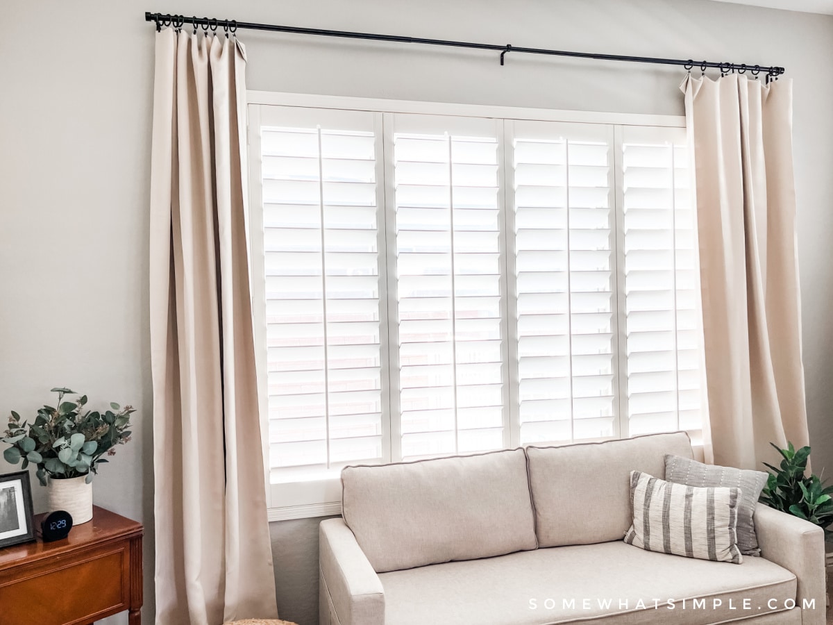 beige couch in a master bedroom under a big window