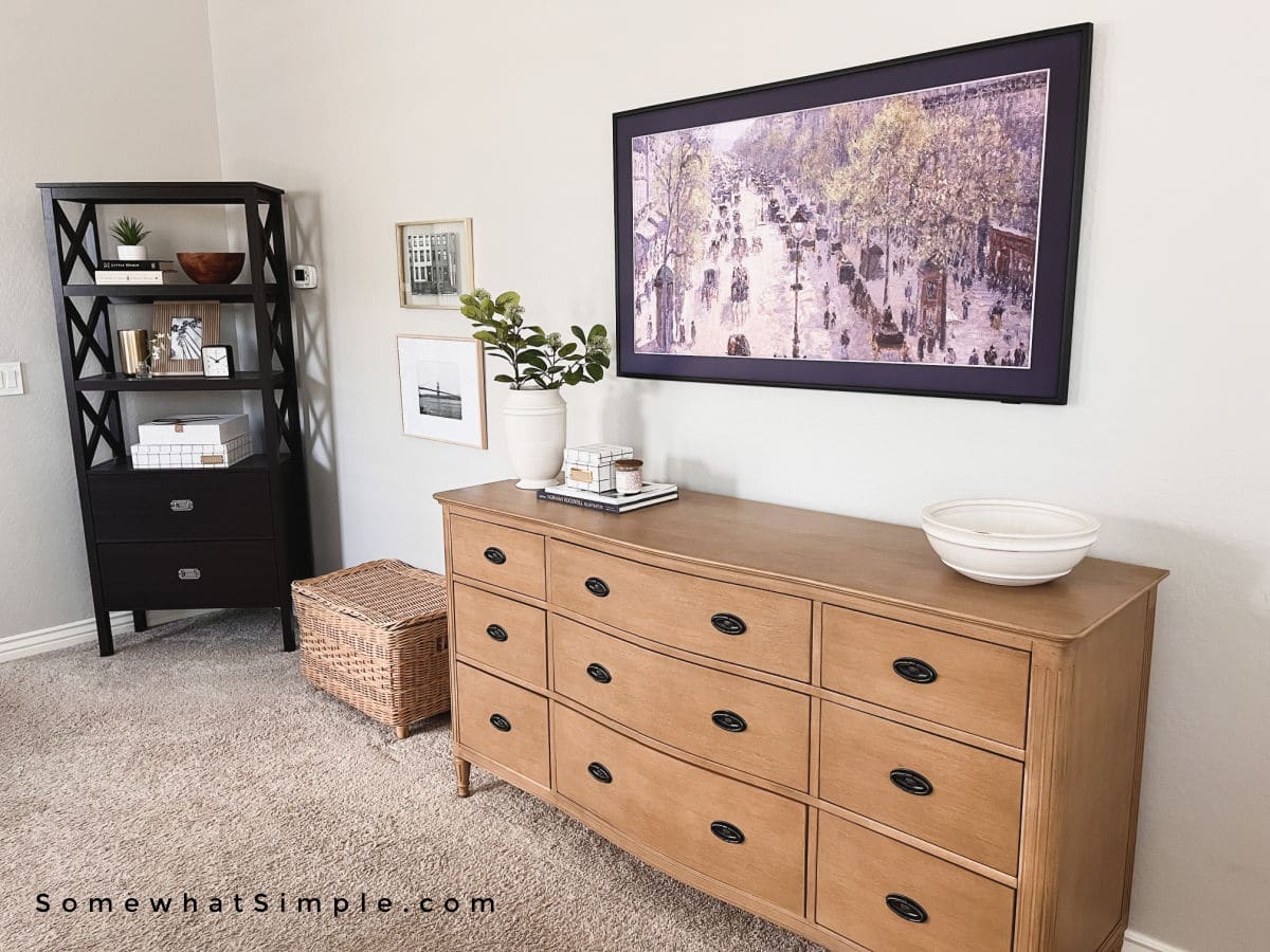 warm wood dresser with frame tv hanging over it