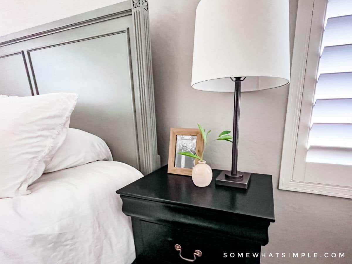top of a black nightstand with a lamp, frame and small plant