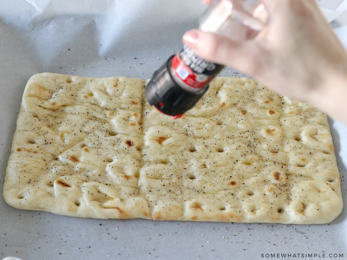 sprinkling salt and pepper on flatbread