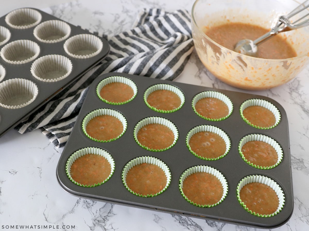 spooning cupcake batter into muffin tins
