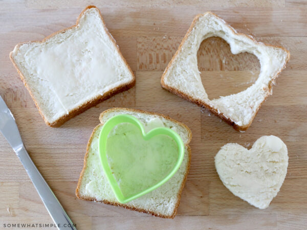 cutting a heart from a slice of buttered bread