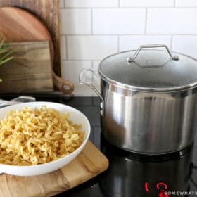 pot of water on a stove next to a bowl of pasta